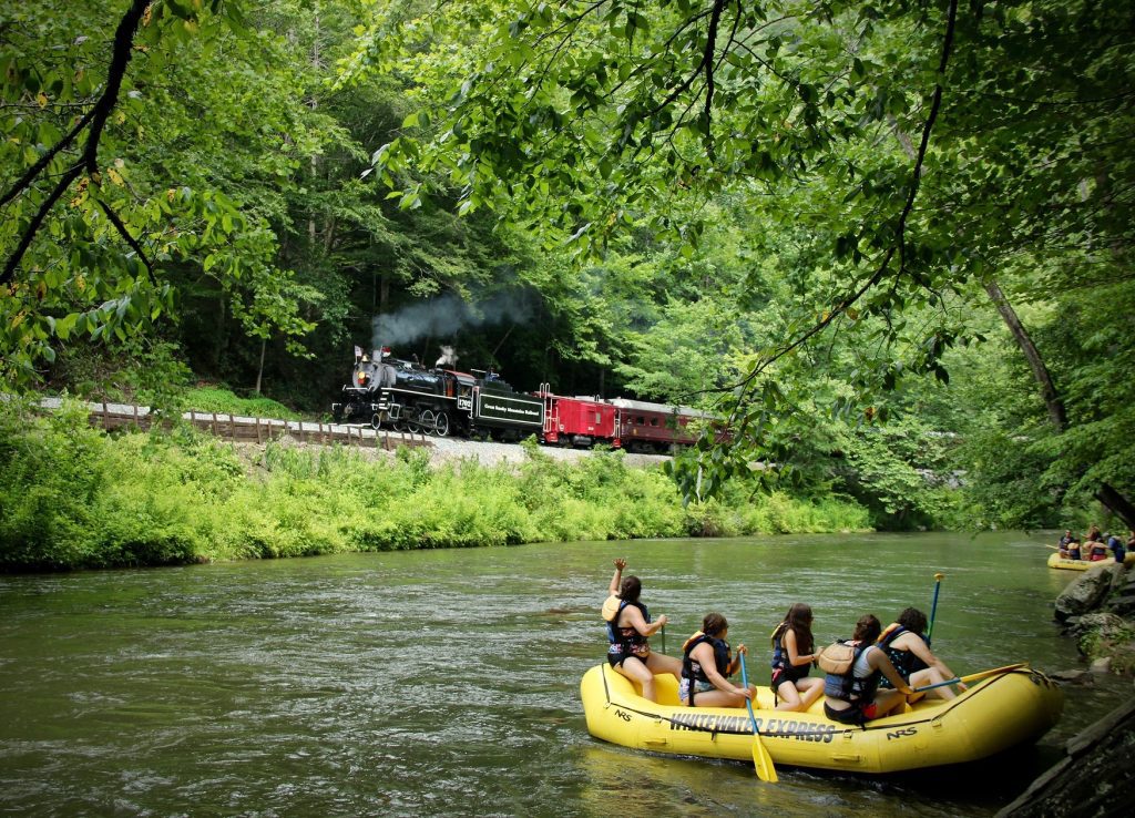 Paddlers on the Nantahala wave to the Great Smoky Mountain Railroad train as it passes by them.