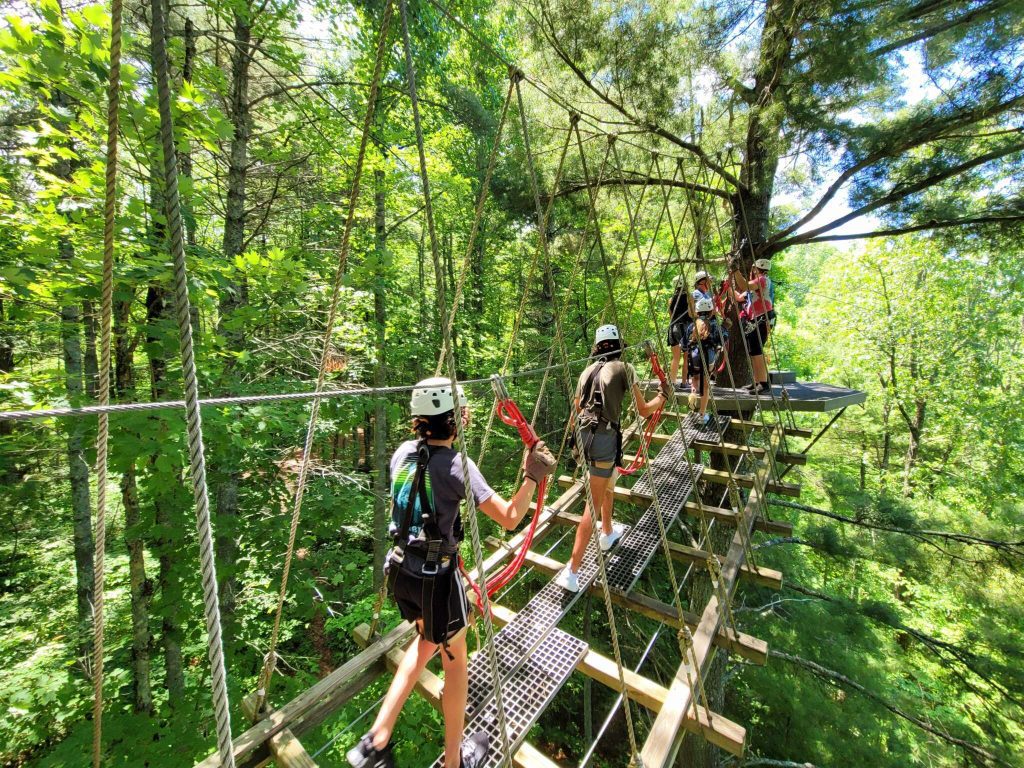 people crossing a cable bridge at highland aerial park in scale mountain nc